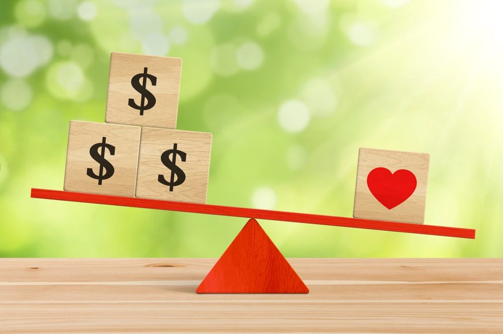 Wooden blocks with dollar signs and a heart on a see-saw, showing the balance between budget and what you love